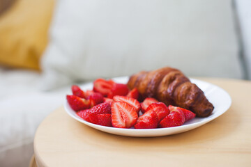 Freshly baked croissant  with strawberries for breakfast at a cafe terrace