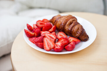 Freshly baked croissant  with strawberries for breakfast at a cafe terrace