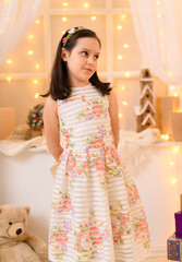 portrait of a child girl in home interior decorated with lights and holiday gifts