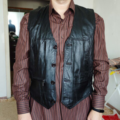 Man in a leather vest at home