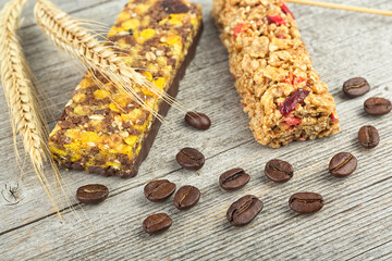 Healthy cereal bars with granola, nuts, dried fruits and coffee beans on a wooden background.