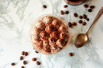 Mini desserts snacks in plastic cups on the table. Tiramisu, traditional Italian dessert on a white marble background..Healthy food and diet concept, restaurant dish delivery