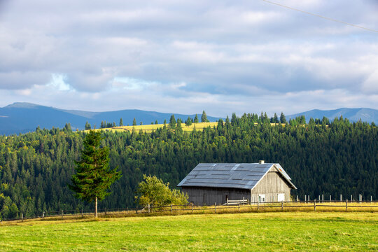 a beautiful landscape with an old wooden cottage on a mountain slope