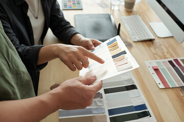 One of two designers pointing at textile sample of pale grey color