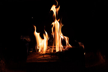 Fire in the fireplace on a dark background. Firewood in flames. An intimate atmosphere by the fire.