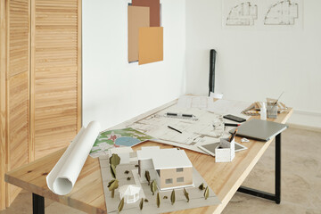 Wooden table with paper house models, sketches of new constructions and mobile gadgets