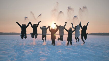 Obraz premium A group of girls friends are throwing snow up at sunset.