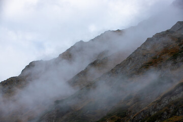 Fototapeta na wymiar The slopes of a mountain in the fog
