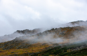 a beautiful landscape with fog on the mountain slope