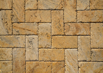 Yellow brown stone pavers background. Neutral texture of a flat brick wall close-up.        