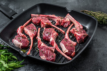 Ready for cooking Raw lamb, mutton chops steaks in a pan with herbs. Black background. Top view