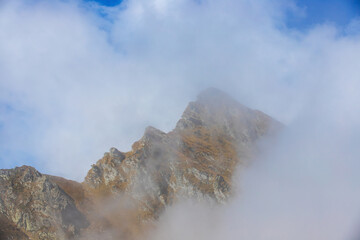 a mountain ridge emerging from the layer of clouds