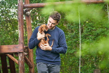 dog Dachshund and her owner, her loving master who holds the dog in her arms, hugs and kisses....