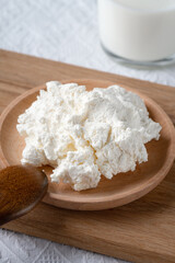 Bowl with fresh cottage cheese and milk on table. Space for text