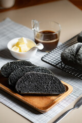 Organic homemade charcoal black bread. set on cafe table with butter and coffee.