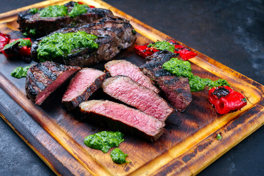 Traditional barbecue dry aged wagyu Brazilian picanha beef steaks served with chili and chimichurri sauce as close-up on a rustic wooden board