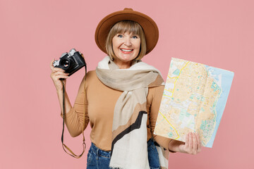 Traveler tourist charming mature elderly senior lady woman 55 years old wears brown shirt hat scarf hold retro vintage photo camera map isolated on plain pastel light pink background studio portrait.