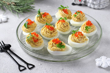 Stuffed eggs with tuna and cheese decorated red caviar, Festive snack on light gray background.