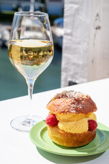 Tarte tropezienne or La Tarte de Saint-Tropez - dessert pastry consisting of filled brioche with cream and fresh berries.and glass of white wine