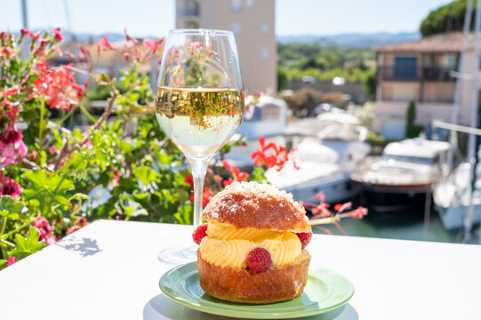 Tarte tropezienne or La Tarte de Saint-Tropez - dessert pastry consisting of filled brioche with cream and fresh berries.and glass of white wine