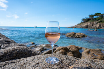 Summer time in Provence, glass of cold rose wine on sandy beach and blue sea near Saint-Tropez, Var department, France