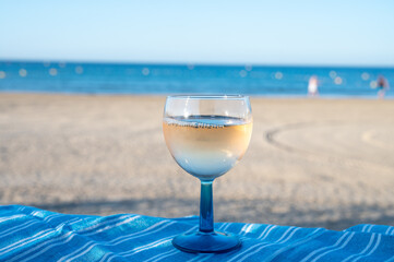 Summer time in Provence, drinking of cold gris rose wine on sandy beach and blue sea near Toulon, Var department, France