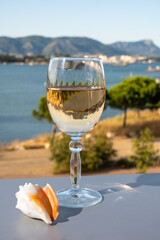 Summer on French Riviera, drinking of cold white or gris rose wine from Cotes de Provence on outdoor terrase with view on harbour of Toulon, Var, France and sea shells