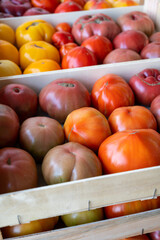 Tasty big ripe french tomatoes in wooden boxes on farmers market in Provence