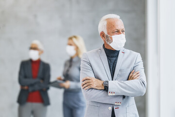 A Business Man With Protective Mask Standing Crossed Arms At The Office During COVID-19 Pandemic