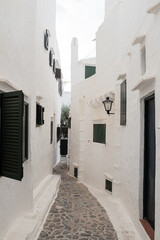 Narrow street corner on a cobble stone street on an old white village in Menorca