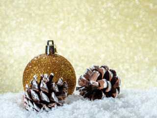 Christmas ball and fir cones on a background of golden glitter.