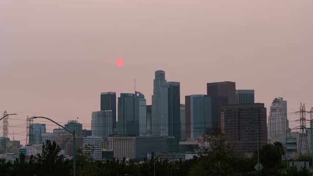 Time lapse day to night transition of red sun over Los Angeles skyline obscured by smoke from KNP Complex wildfire in California in 2021