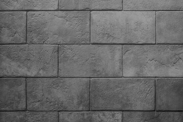 The wall is made of dark gray stone blocks with scuffs and damage. Dark gray background with brick texture.
