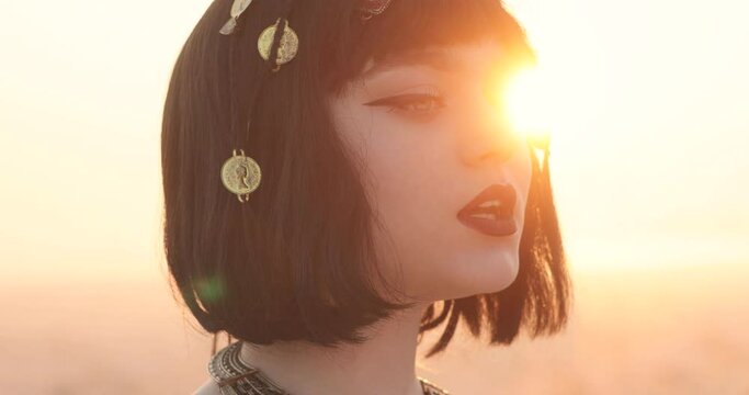 profile of attractive young woman with short black hair. jewelry in hair. beautiful sunset. the sun's rays in the girls hair.