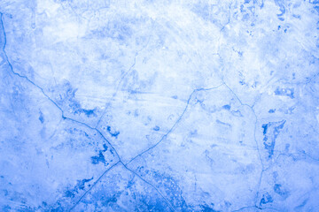 A concrete wall with scuffs and cracks of blue color. Cold, blue background with cement texture.
