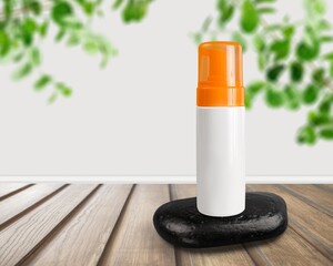 A blank tube of cosmetics on a stone among the leaves. The concept of natural plant cosmetics.