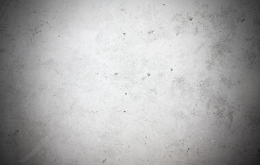 A concrete wall with dots and scuffs of light gray color. Light gray background with cement texture and vignette.