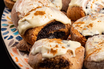 Poppy seeds buns on the ceramic plate on the black background