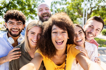 Happy multiracial friends taking a selfie portrait with mobile phone - Diverse group of young teenage students having great time together while hugging each other outdoors - Millennial people concept