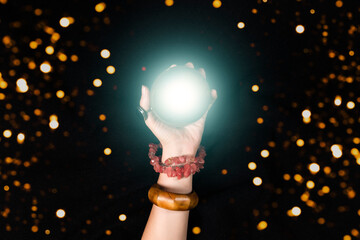 Fortune teller or witch hand and a glowing magic ball. Halloween, magic or witchcraft and tricks concept