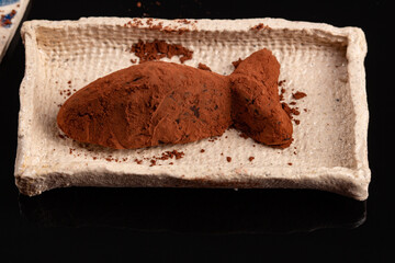 Truffle chocolate made of vegan ganache cream on the pottery plates and the black background