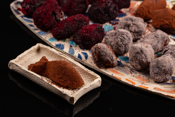Truffle chocolate made of vegan ganache cream on the pottery plates and the black background