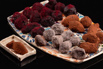 Truffle chocolate made of vegan ganache cream on the pottery plates and the black background