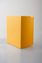 Yellow orange closed cardboard box or carton on grey background, template, mockup, sideview.