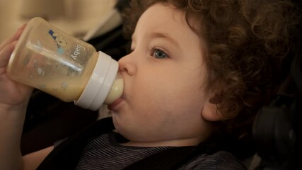 Baby feeding from a bottle. Drinking milk from Bottle. Drinking milk Close Up.  little kid drinking his milk. mother feeding baby drinking from milk bottle loving mom caring for infant 