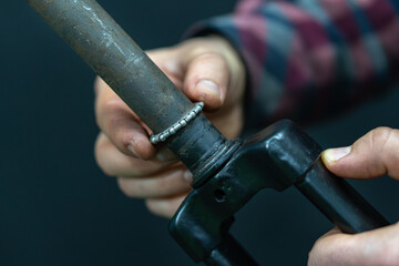 Professional bicycle repair in the workshop. The mechanic repairs the old rigid fork of the bike, replacement of the steering column bearing. Details of a bicycle fork on a black background.