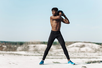 Fitness African American man doing workout twist exercise with medicine ball weight, outdoors on...