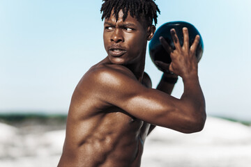 African American crossfit man, fitness man holding abdominal workout ball, outdoors