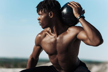 Portrait of athletic workout, African American man, with ball outdoors in nature