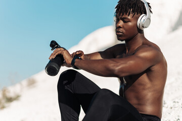 African American athlete exercising with fitness bracelet, man exercising outdoors in the mountains